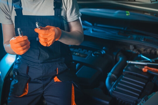 Auto mechanic installing a new spark plugs into the engine.