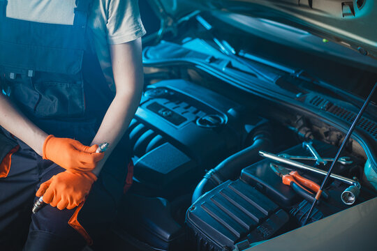 Auto mechanic installing a new spark plugs into the engine.