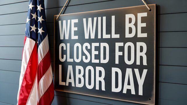 A sign hanging on a dark blue wall next to an american flag that says we will be closed for labor day