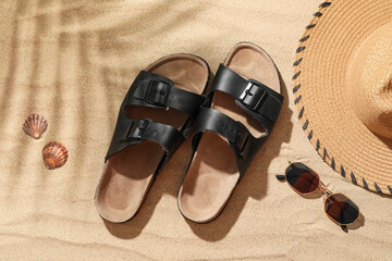 Naklejka premium Stylish mens sandals with sunglasses, seashells and wicker hat on sand