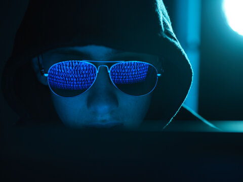 Cyber Crime, reflection in spectacles of virus hacking a computer, close up of face