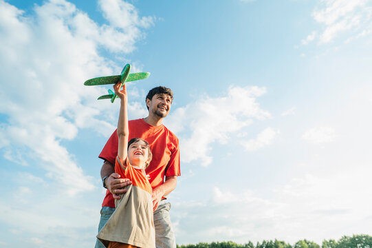Father and son launch a toy airplane in the park