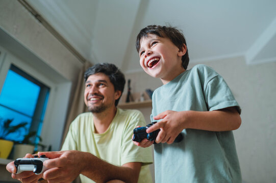 Father and son playing a video game together at home