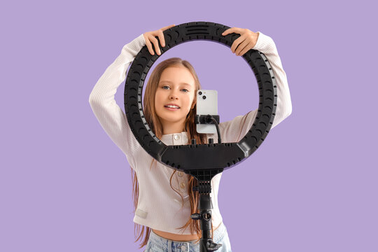 Teenage blogger with ring light on lilac background