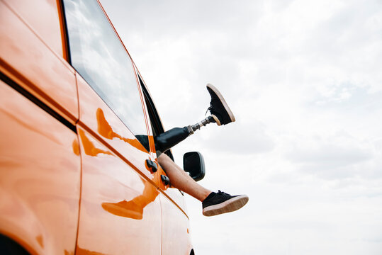 Legs of prosthetic young man dangling out of camper van window