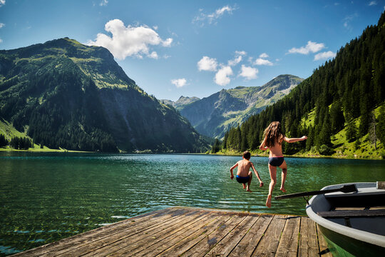 Sister and brother jumping into Vilsalpsee lake