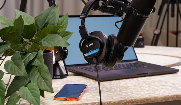 Podcast studio equipment professional headphones microphone laptop smartphone desk plant setup