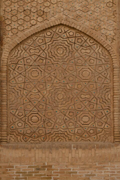 Intricate geometric brickwork panel with turquoise tile accents on a historic facade in Bukhara. Ideal for travel, architecture, and cultural heritage projects.