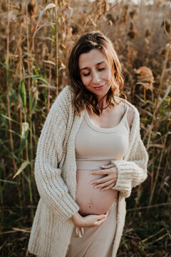 Pregnant woman holding her baby bump in an autumn field