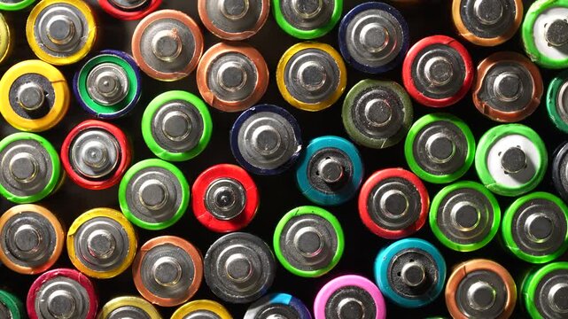 Colorful used alkaline batteries background pattern. Top view of many assorted colorful alkaline batteries, close up. Great for recycling, environmental conservation and renewable energy concepts