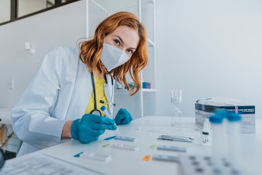Doctor wearing protective face mask testing sample on test cassettes at examination room