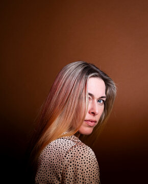 Serious woman in polka dot blouse looking over shoulder indoors