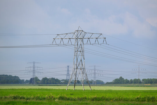 Power pylons and lines stretch across a green pasture in Groningen