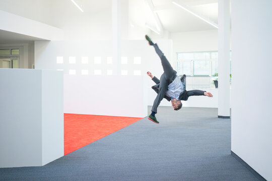 Businessman jumping mid-air on office floor