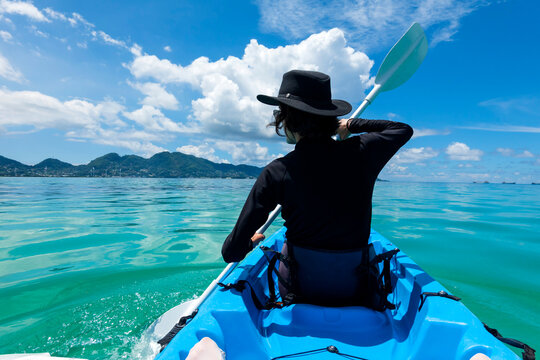 Seychelles, Mahe, back view of black dressed man with hat kayaking
