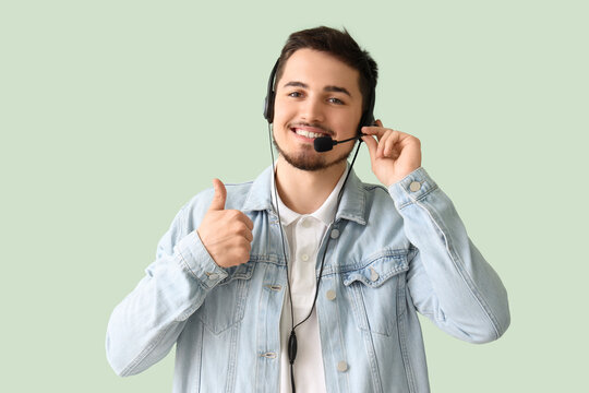 Male technical support agent showing thumb-up on mint background