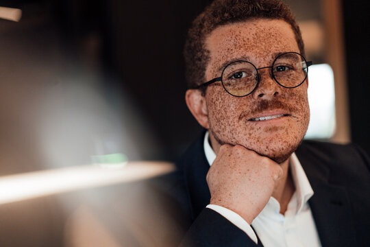 A confident businessman with freckles sits in a modern office