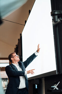 Mid adult caucasian businessman with freckles pointing at a blank touchscreen in an office