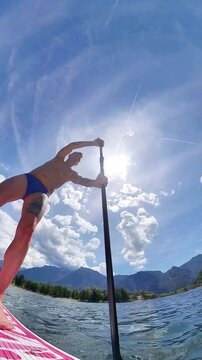 A man practices stand-up paddleboarding in Lake Levico, with a circular chamber movement from bottom to top