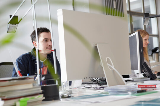 A man and woman use a computer in a bright Cologne office