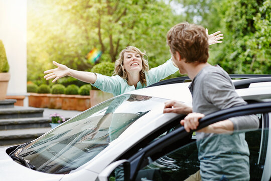 Happy woman with outstretched arms looking at man at car
