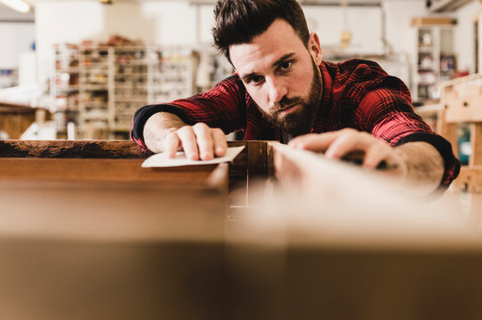 Man treating wood in workshop with sand paper