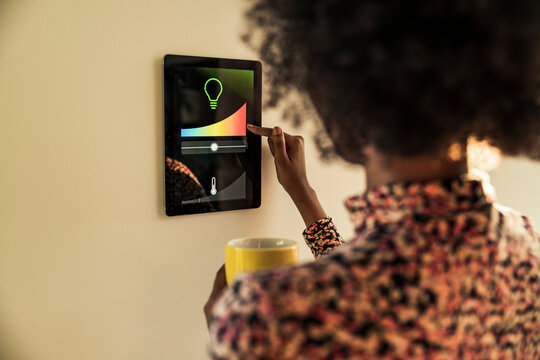 Woman with cup adjusting temperature graph on home automation device