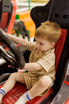 Toddler child playing on orange motorbike slot machine at kids club