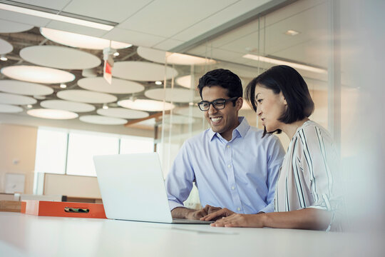 Businessman and woman using laptop together