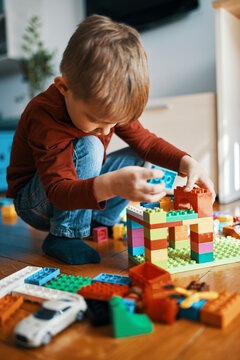 Little boy playing with building bricks on the floor at home