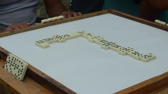 Close up Four players enjoy domino game, interaction at family gathering intense gaming session