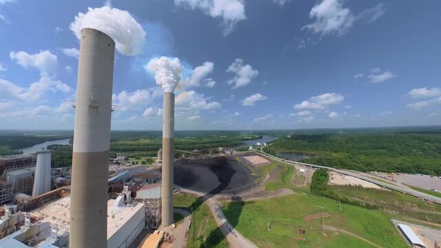 Aerial flythrough of 2 smokestacks at a fossil fuel refinery on the Cumberland River in Cumberland City, Tennessee