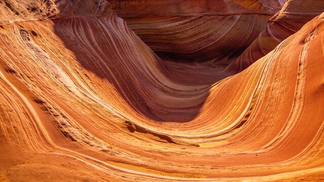 Intricate swirling patterns of layered sandstone create abstract flowing textures in a unique geological formation suitable for backgrounds and design projects.