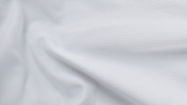 Close up of soft white sports clothing fabric with football shirt jersey texture. White jersey clothing fabric with sports wear texture. White sports fabric background with clean textile surface.