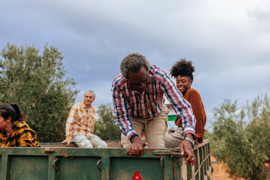 Diverse farmers on a trailer in an olive grove