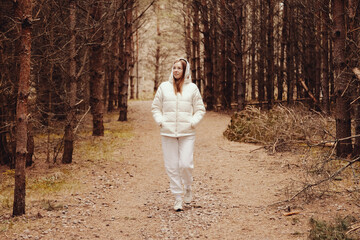 Fototapeta premium Walking Through a Serene Forest Path in Cozy Winter Attire Surrounded by Tall Trees