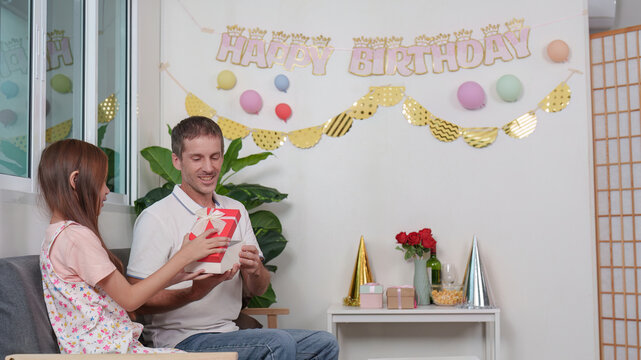Happy father receiving birthday gift from daughter at home celebration