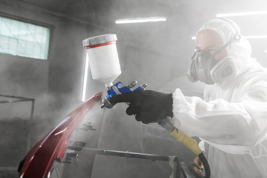 Car paint job by professional worker, car painting procedure in car service, body paint garage. 
