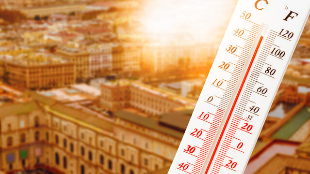Heatwave in a city during summer with a thermometer showing high temperatures and bright sunlight