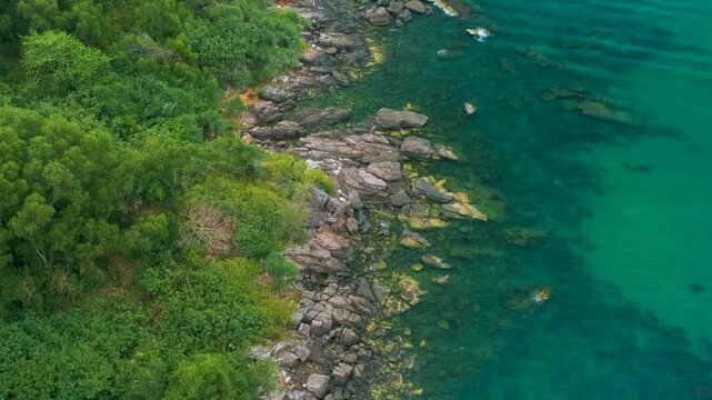 Aerial view of rocky coast on Phu Quoc Island, Vietnam, surrounded by lush green rainforest, palm trees and clear turquoise sea water. Sustainable tourism and travel in Asia
