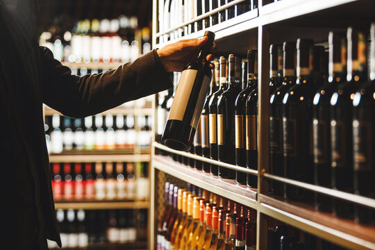 Sommelier Selecting Fine Wine Bottle From Cellar Collection While Consulting Description
