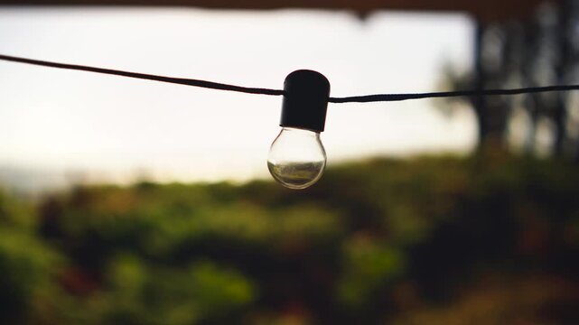 Van Life POV &ndash;String Light Bulb Close-Up of Looking Out Campervan Window at Ferns and Sparkling Sea
