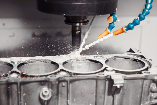 CNC milling machine grinds holes in car engine with coolant. Process of setting up engine cylinder blocks on a numerically controlled machine. 