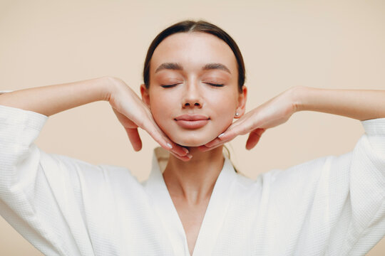 Young beautiful woman doing face building yoga self massage with hands. Facial gymnastics and rejuvenating female skin exercises. Model nude make up. Plastic surgery.