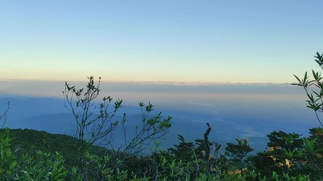 Breathtaking panoramic vista from a towering mountain peak at early dawn, showcasing a serene and expansive natural landscape with an ethereal, clear blue sky, soft morning light, and tranquil