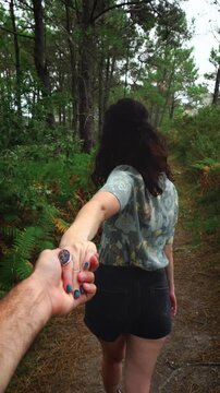 Romantic Man and Woman Couple Grabbing and Holding Hands Walking Through Autumn Forest path with Pine trees