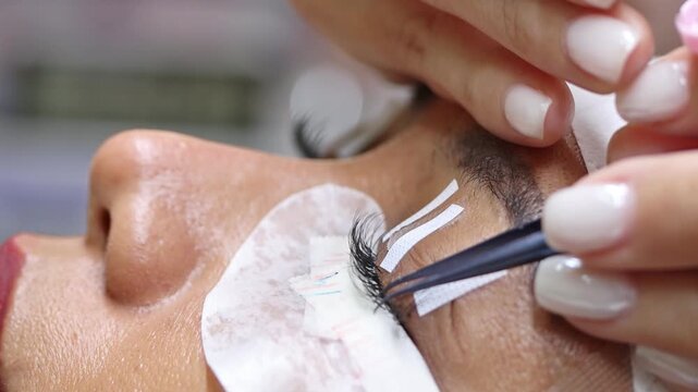 The process of eyelash extension and volume increase in a professional beauty salon, close-up view