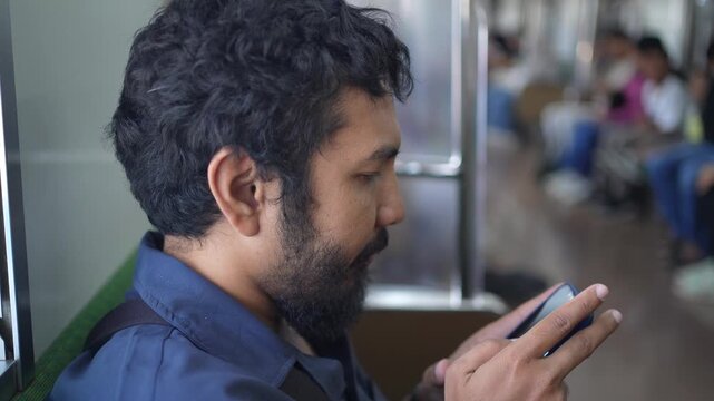 Close Up of Asian Man Using Smartphone During Train Commute in Indonesia