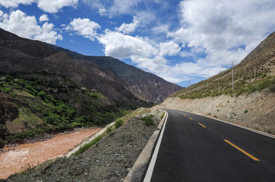 Scenic road winding through mountainous landscape under cloudy sky