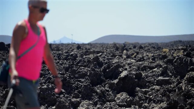 Female Hiker Trekking with a Miniature Pinscher Dog Along a Volcanic Trail in the Lanzarote Badlands